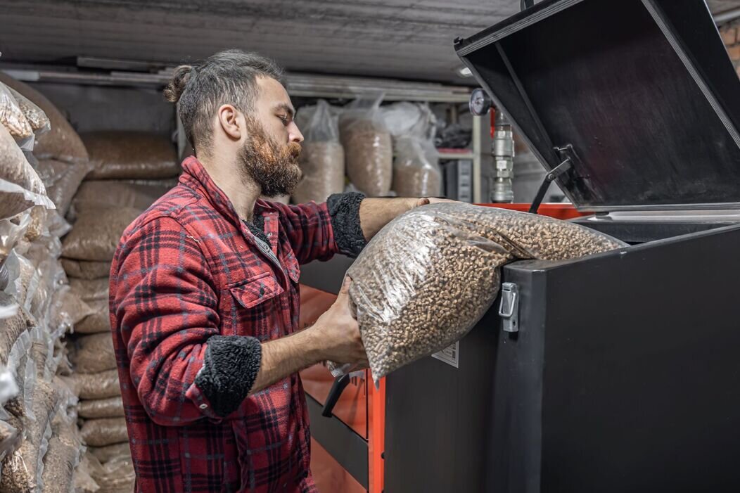 Homme qui charge des pellets dans une chaudière 